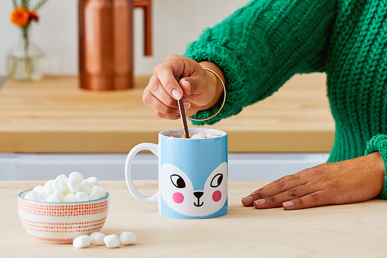 Customised Cricut Mug Press Mug sits on a kitchen counter. It has a cute animal face on with blue fur. A bowl of white marshmallows is on the left of the mug.